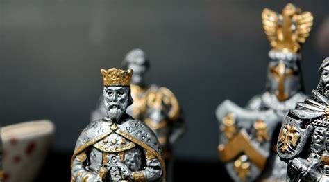 A photo of several small, pewter figures with golden accents, which appear to be a kind, a bishop, and a knight. The photo shows only the busts of these figures. 
