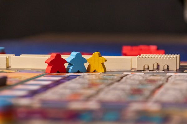 A photo of three meeples on a board game board