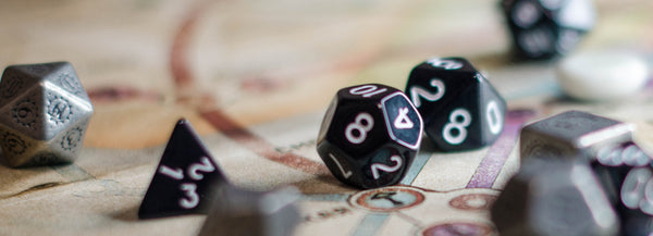 A photo of several black dice with white numbering, scattered on a brown-ish map