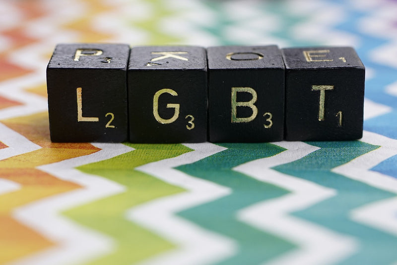 A photo of 4 lettered dice, spelling out "LGBT" on top of colorful zigzag stripes