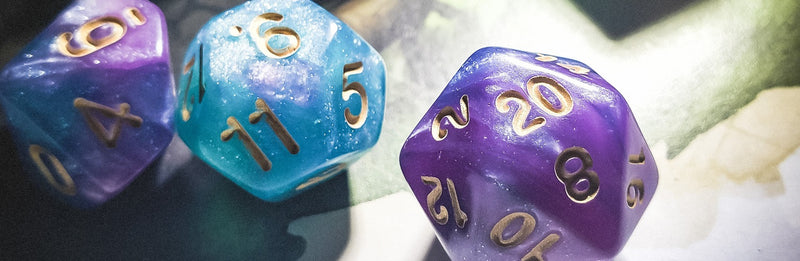 A photo of 3 dice against a green and yellow background. The dice are shimmery, purple and blue, and have gold numbering. They are a d10, a d12, and a d20. The numbers 6, 9, and 20 are showing respectively.